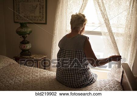 Pensive older woman looking out bedroom window View Large Photo Image Stock Image - Pensive older woman looking out bedroom window. Fotosearch