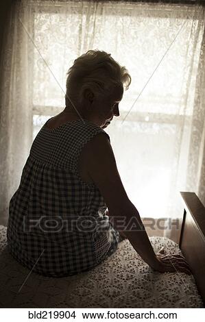 Pensive older woman sitting on bed View Large Photo Image Picture - Pensive older woman sitting on bed. Fotosearch