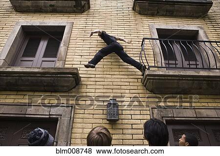 People watching man climb on outside of building View Large Photo Image Stock Photo - People watching man climb on outside of building. Fotosearch