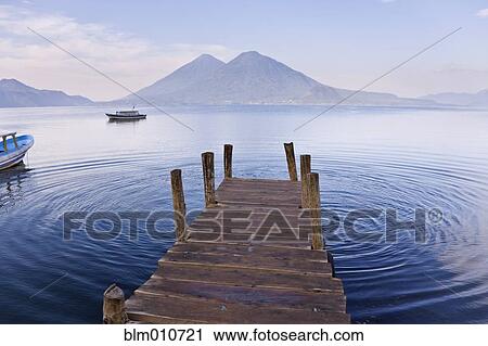 Pier on lake with mountain in distance View Large Photo Image Stock Image - Pier on lake with mountain in distance. Fotosearch