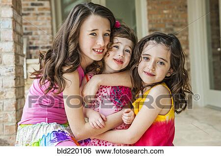 Playful sisters hugging outdoors View Large Photo Image Stock Photograph - Playful sisters hugging outdoors. Fotosearch