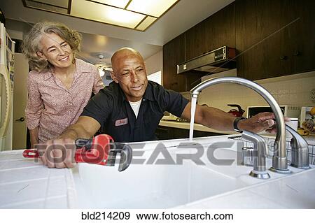 Plumber testing sink for woman in kitchen View Large Photo Image Stock Photo - Plumber testing sink for woman in kitchen. Fotosearch