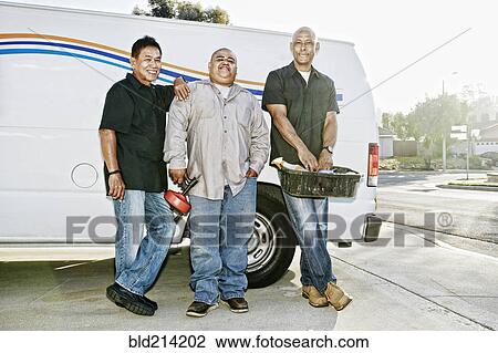 Stock Image - Plumbers smiling near van. Fotosearch