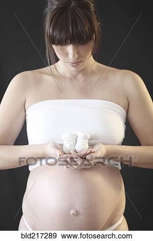 Pregnant Caucasian woman holding baby booties View Large Photo Image Stock Photo - Pregnant Caucasian woman holding baby booties. Fotosearch