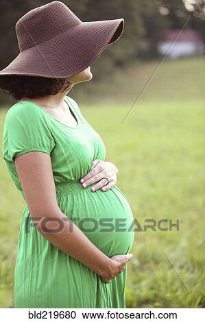 Pregnant Caucasian woman holding belly in field View Large Photo Image Stock Image - Pregnant Caucasian woman holding belly in field. Fotosearch