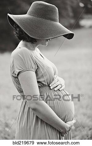 Stock Photo - Pregnant Caucasian woman holding belly in field. Fotosearch