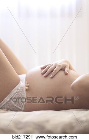 Stock Image - Pregnant Caucasian woman holding her belly. Fotosearch