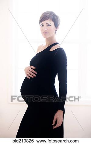 Stock Photograph - Pregnant woman wearing evening gown. Fotosearch