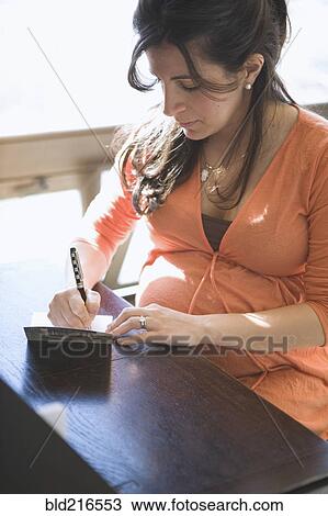 Pregnant woman writing card at table View Large Photo Image Stock Image - Pregnant woman writing card at table. Fotosearch