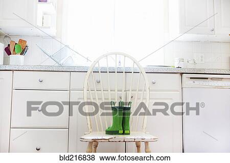 Stock Photo - Rain boots of child on chair near kitchen sink. Fotosearch