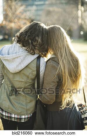 Stock Image - Rear view of Caucasian women hugging outdoors. Fotosearch
