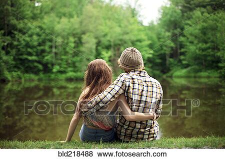 Stock Photo - Rear view of couple hugging near lake. Fotosearch