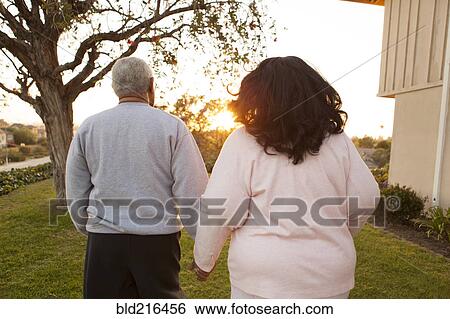 Stock Photograph - Rear view of couple walking in backyard. Fotosearch