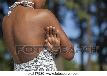 Stock Image - Rear view of girl wearing swimsuit near trees. Fotosearch