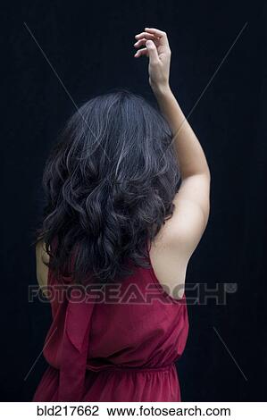 Stock Image - Rear view of mixed race woman raising her arm. Fotosearch