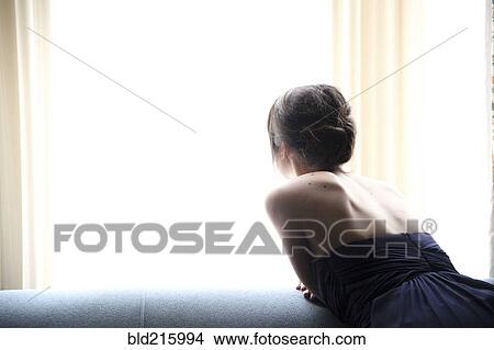 Picture - Rear view of woman in evening gown looking out window. Fotosearch