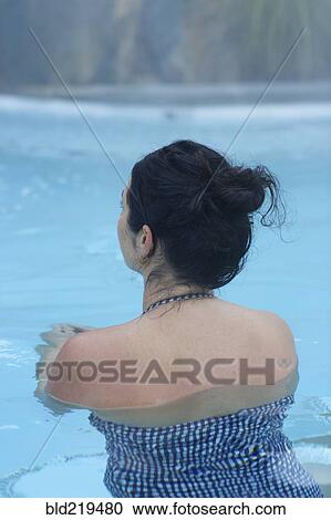 Stock Image - Rear view of woman swimming in pool. Fotosearch