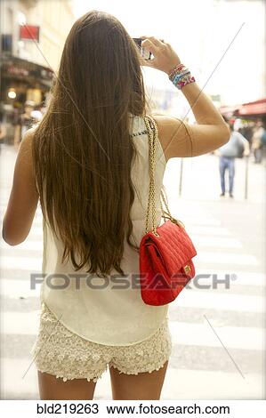 Stock Image - Rear view of woman taking photographs. Fotosearch