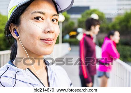 Stock Image - Runner listening to earbud in city. Fotosearch