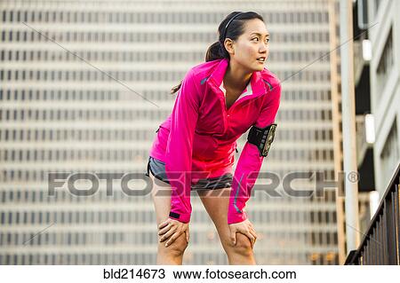 Stock Image - Runner resting near highrise building. Fotosearch