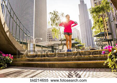 Stock Photography - Runner standing on city steps near high rise buildings. Fotosearch
