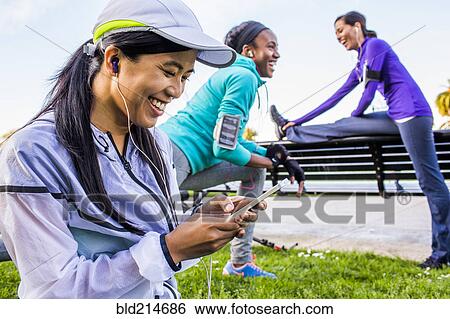 Stock Photograph - Runner using cell phone in urban park. Fotosearch
