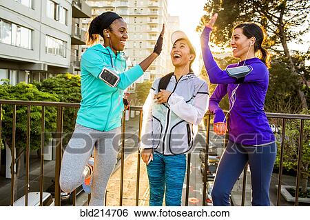 Stock Photograph - Runners high-fiving in city. Fotosearch