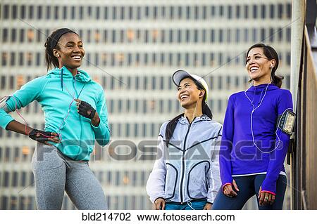 Stock Image - Runners laughing near highrise building. Fotosearch