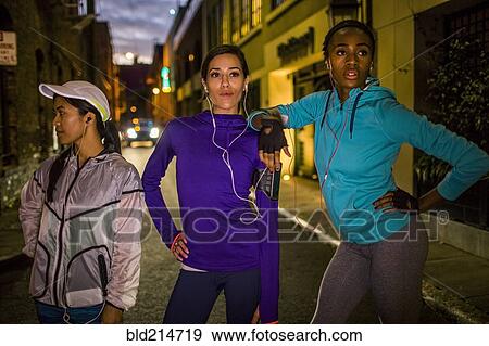 Runners standing on city street at night View Large Photo Image Stock Photo - Runners standing on city street at night. Fotosearch