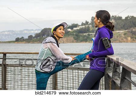 Stock Photo - Runners stretching at waterfront. Fotosearch