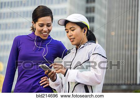 Runners using cell phone near high rise buildings View Large Photo Image Stock Photograph - Runners using cell phone near high rise buildings. Fotosearch
