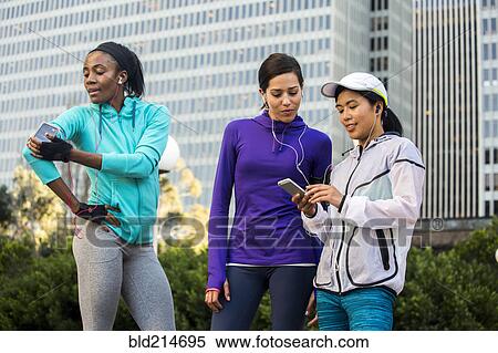 Runners using cell phone near high rise buildings View Large Photo Image Stock Photography - Runners using cell phone near high rise buildings. Fotosearch