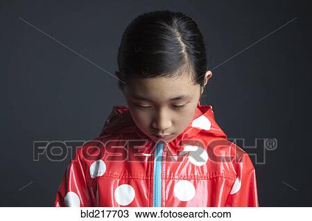 Stock Image - Sad Asian girl wearing raincoat. Fotosearch
