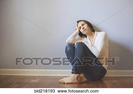 Stock Image - Sad Caucasian woman sitting on floor. Fotosearch