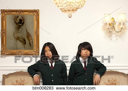 Stock Image - Sad Vietnamese children standing in elegant room. Fotosearch