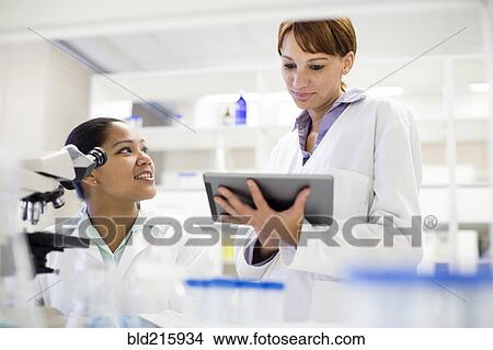 Picture - Scientists using digital tablet and microscope in laboratory. Fotosearch