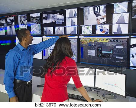 Stock Image - Security officers watching surveillance cameras. Fotosearch