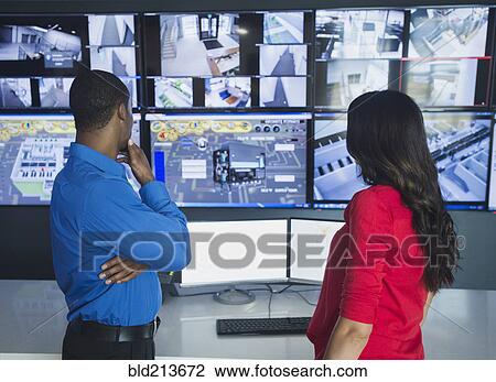 Stock Image - Security officers watching surveillance cameras. Fotosearch
