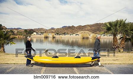 Senior Caucasian couple carrying kayak View Large Photo Image Stock Photograph - Senior Caucasian couple carrying kayak. Fotosearch
