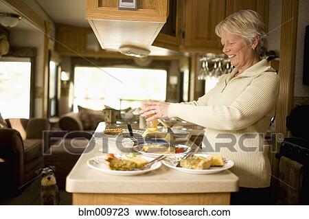 Stock Image - Senior Caucasian woman cooking in motor home. Fotosearch