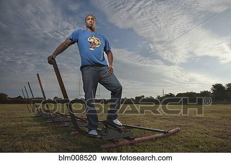 Stock Image - Serious African American man standing on football field. Fotosearch