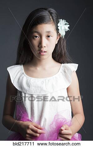 Stock Image - Serious Asian girl wearing flower in her hair. Fotosearch