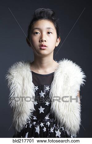 Stock Image - Serious Asian girl wearing furry vest. Fotosearch