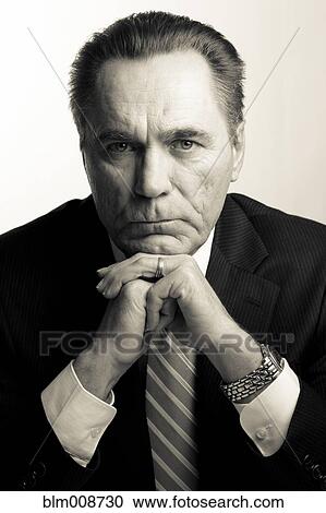 Stock Image - Serious Caucasian businessman with hands on chin. Fotosearch