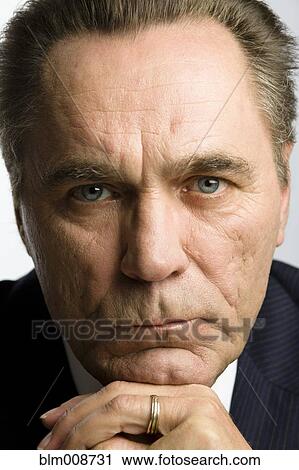 Stock Image - Serious Caucasian businessman with hands on chin. Fotosearch
