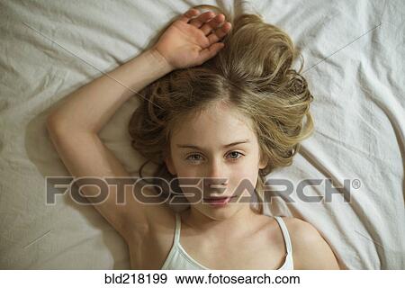 Serious Caucasian girl laying on bed View Large Photo Image Stock Photo - Serious Caucasian girl laying on bed. Fotosearch