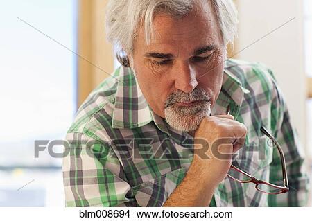 Serious Caucasian man holding eyeglasses View Large Photo Image Picture - Serious Caucasian man holding eyeglasses. Fotosearch