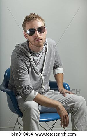 Serious Caucasian man sitting in chair View Large Photo Image Picture - Serious Caucasian man sitting in chair. Fotosearch