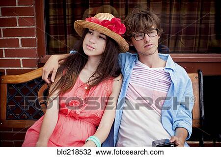 Stock Image - Serious couple sitting on bench. Fotosearch