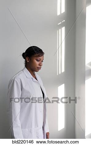 Serious doctor standing at window View Large Photo Image Stock Photograph - Serious doctor standing at window. Fotosearch